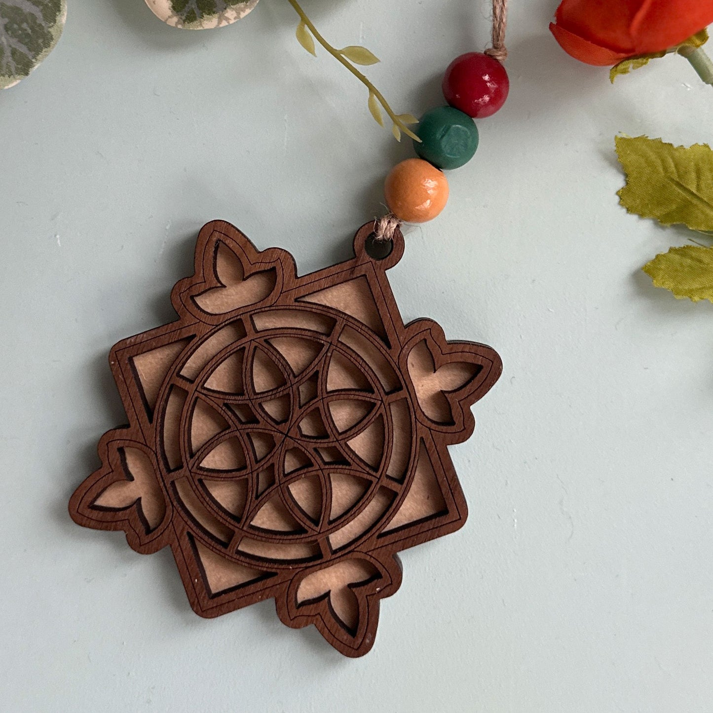Wooden stained glass Christmas ornament on a light gray background with decorative elements.