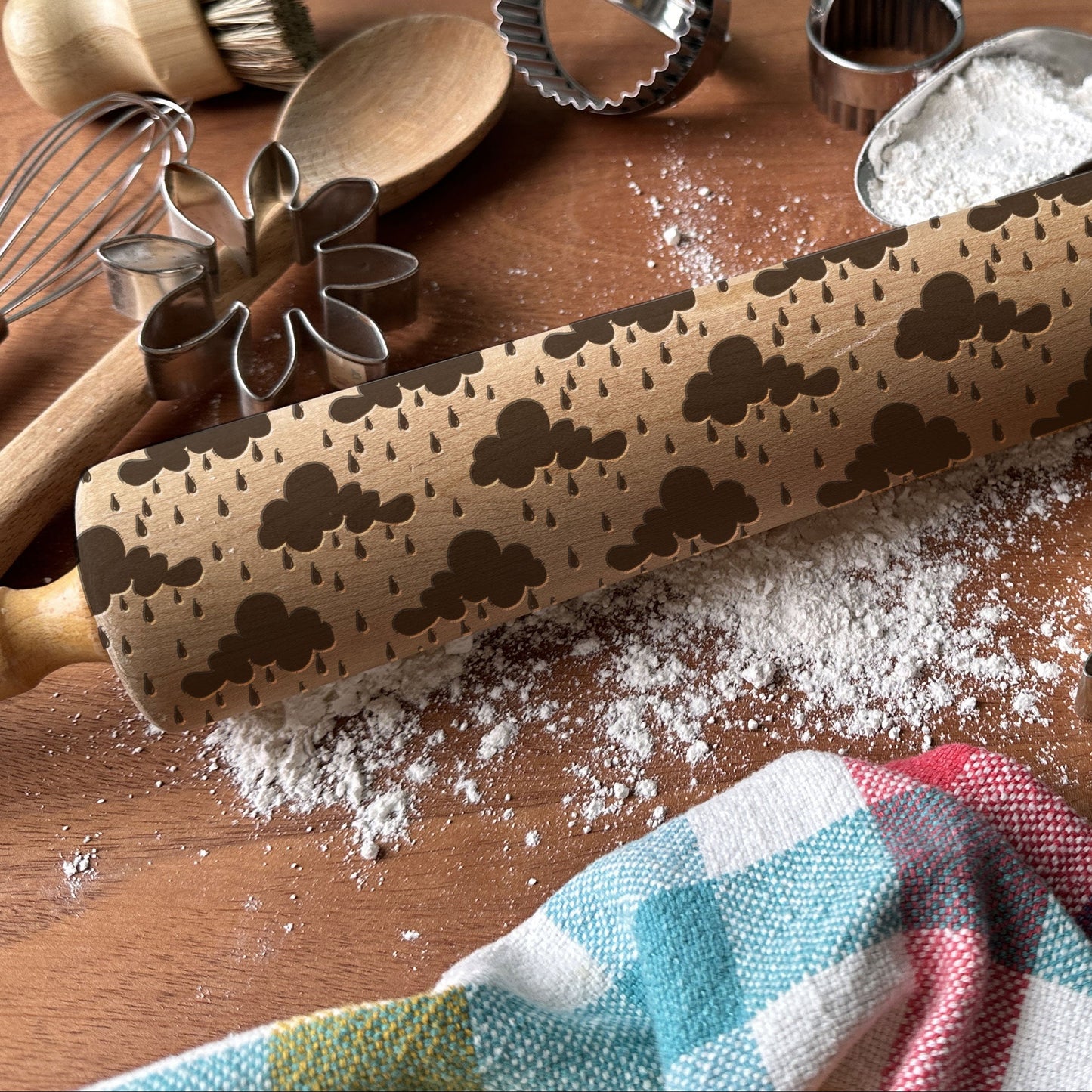 Decorative rolling pin with embossed patterns on a wooden surface with baking tools.