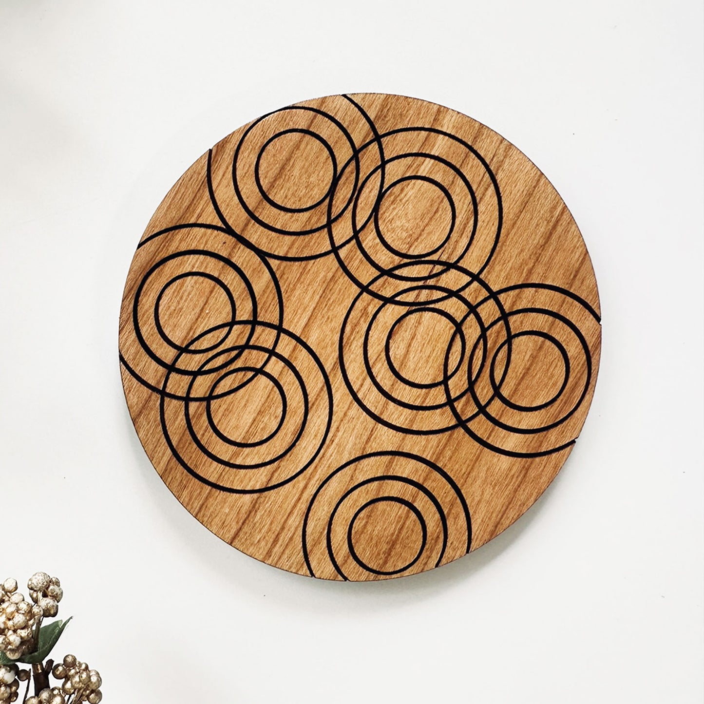 Wooden coaster with circular laser cut design on a white background