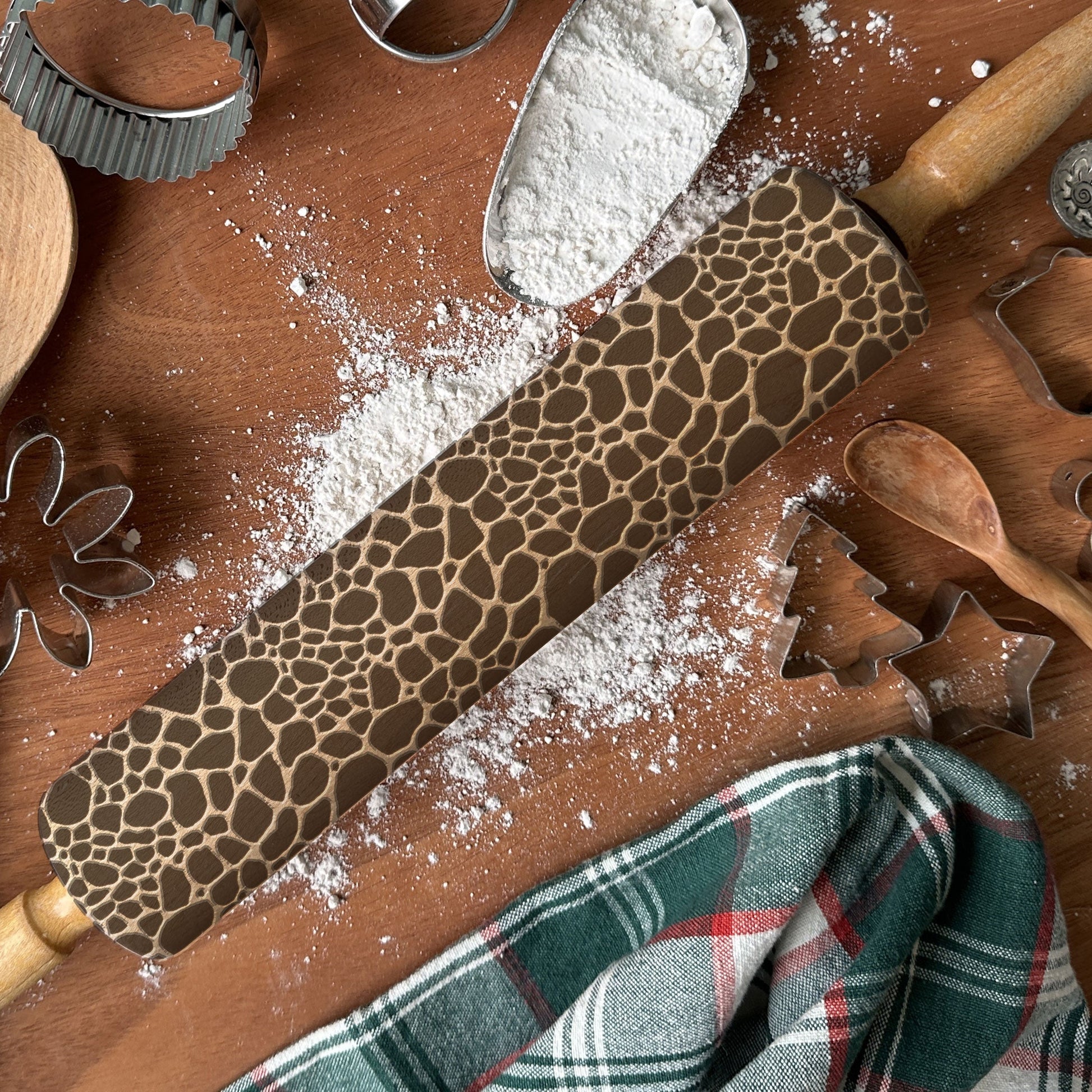 Wooden rolling pin with a pattern on a wooden surface with flour and baking tools.