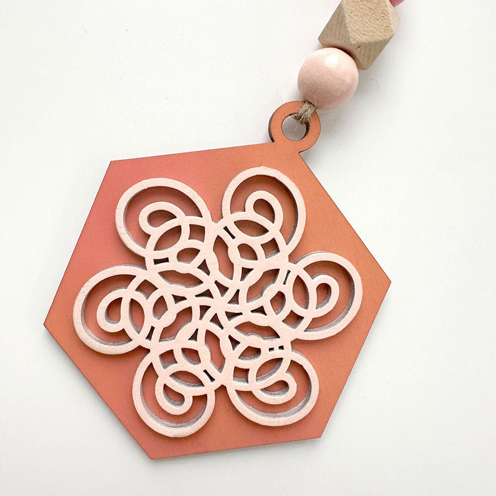 Decorative hanging ornament with geometric design and wooden beads on a white background