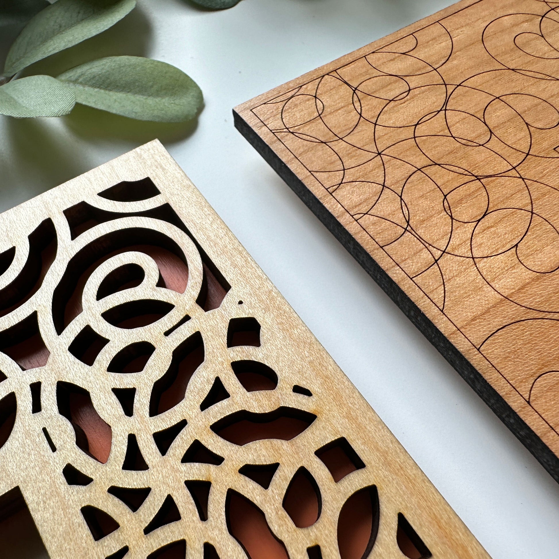 Two wooden panels with intricate cut-out patterns on a white surface.