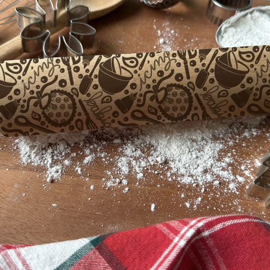 Decorative rolling pin with baking-themed design on a wooden surface with flour.
