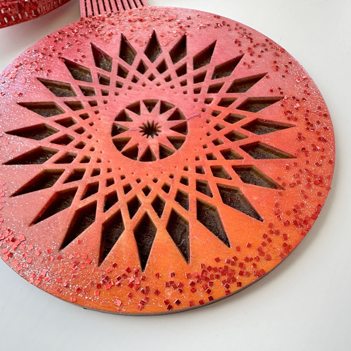 Decorative red and orange circular object with geometric pattern on a white background