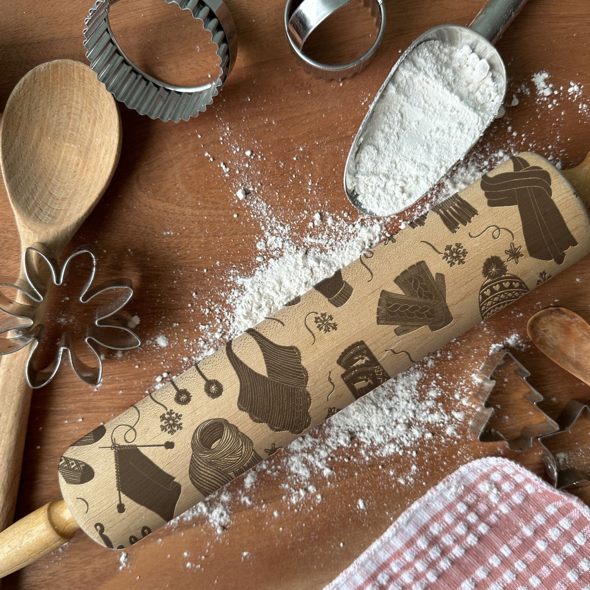 Wooden rolling pin with cookie cutters and flour on a wooden surface